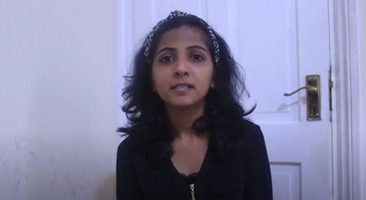 a screenshot of the video creator, Blessy, sitting in front of a door and speaking to camera.
